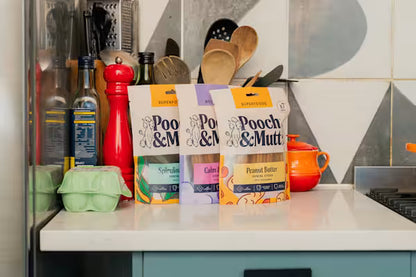 Pooch & Mutt dog subscription box with various dog food and treats, arranged on a table, promoting ongoing pet nutrition.